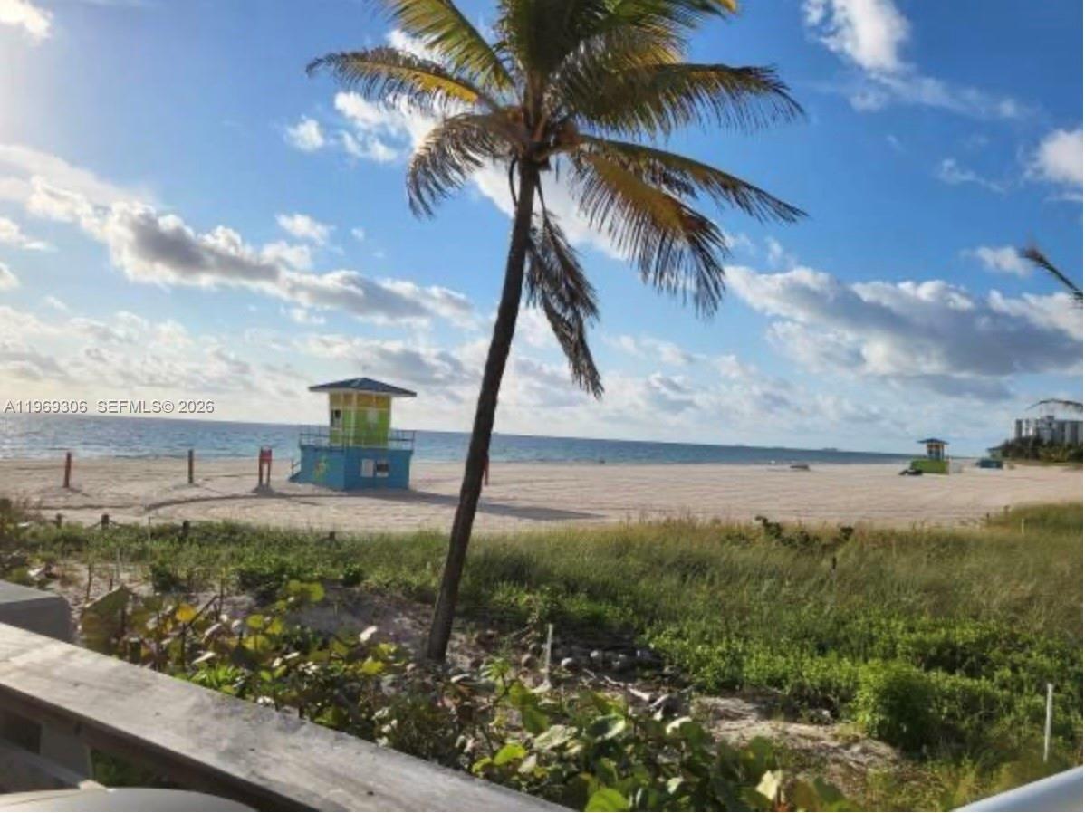 A palm tree stands in the foreground overlooking a sandy beach with two lifeguard towers — 3220 NE 10th St # 5, Pompano Beach FL 3306, POMPANO BEACH, FL