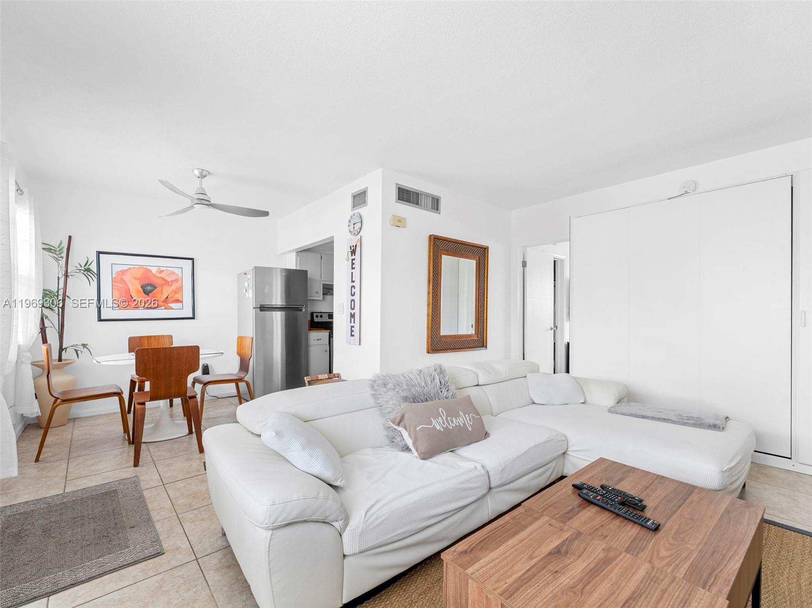 A living room and dining area with a white sectional sofa, wooden table, and refrigerator — 3220 NE 10th St # 5, Pompano Beach FL 3306, POMPANO BEACH, FL