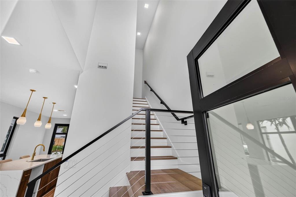 A modern entryway features a staircase with wood treads and a black metal railing — 3603 1ST AVENUE N, ST PETERSBURG, FL