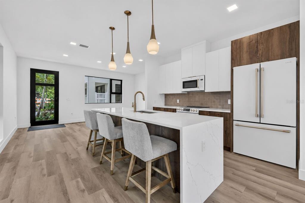 A modern kitchen features a white quartz island, wood cabinetry, and three hanging pendant lights — 3603 1ST AVENUE N, ST PETERSBURG, FL
