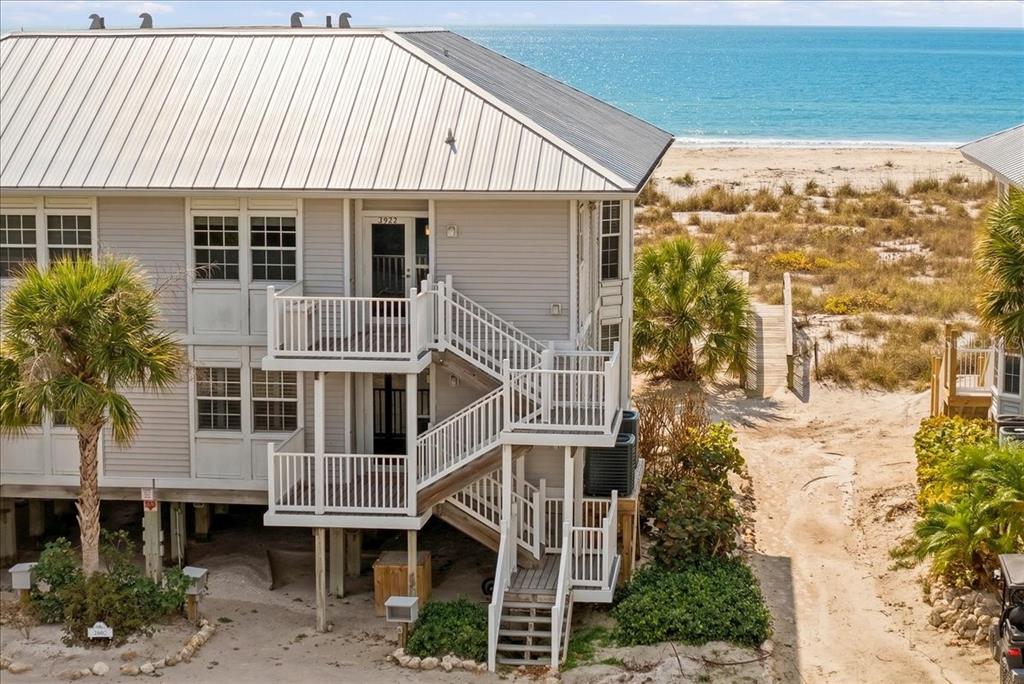 An elevated beach house features white siding, a metal roof, and an exterior staircase — 7466 PALM ISLAND DRIVE UNIT 2922, PLACIDA, FL