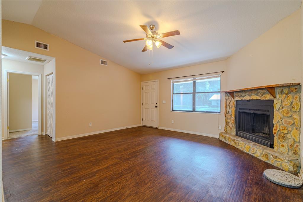 A living room features dark wood-look flooring, a stone fireplace, and a ceiling fan — 6362 NW 64TH TERRACE, OCALA, FL