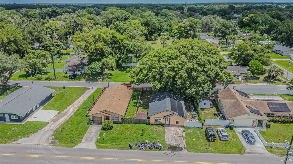 An aerial view shows three suburban houses with driveways and yards along a paved road — 5512 20TH STREET, ZEPHYRHILLS, FL