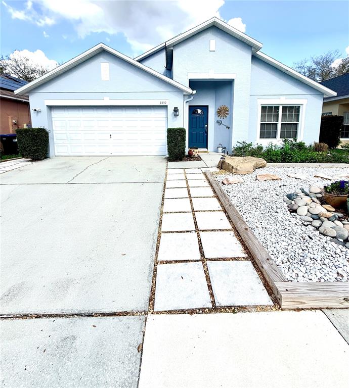 A light blue single-story house features a two-car garage, a blue front door, and landscaping — 4339 NORTHERN DANCER WAY, ORLANDO, FL