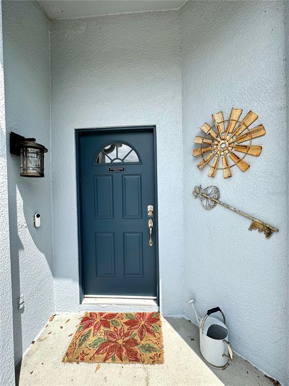 A blue front door with a decorative metal windmill and key wall art — 4339 NORTHERN DANCER WAY, ORLANDO, FL