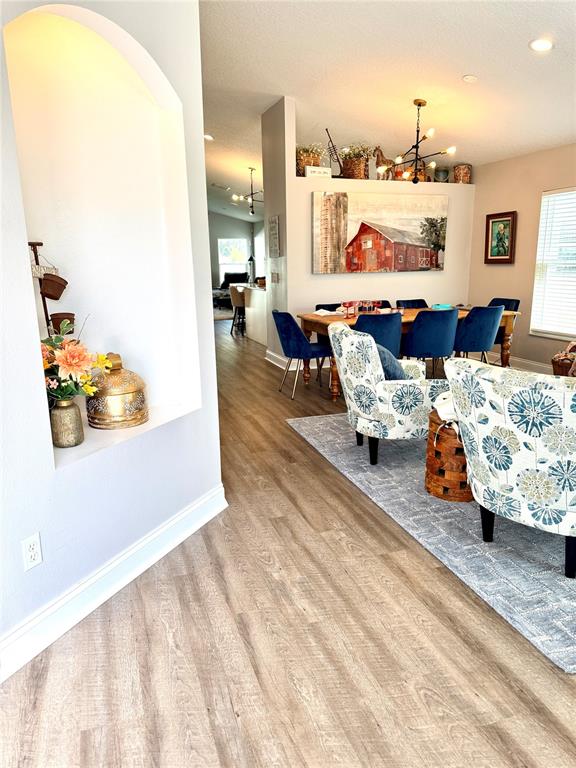 A dining area and living space feature wood-look flooring, an arched wall niche, and furniture — 4339 NORTHERN DANCER WAY, ORLANDO, FL