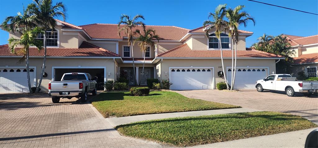 A two-story residential building with a tile roof, two garages, and two pickup trucks parked outside — 197 TROPICANA DRIVE UNIT 1512, PUNTA GORDA, FL