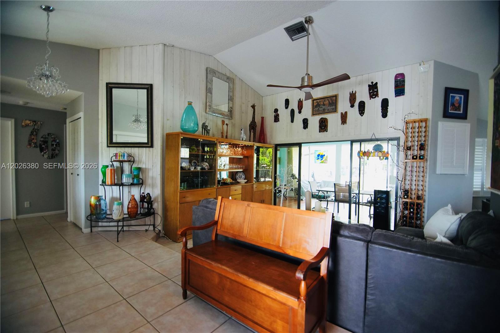 A living room features a vaulted ceiling, wood-paneled walls, a wooden bench, and display cabinets — 150 SW 127th Ave, Plantation FL 33325, PLANTATION, FL
