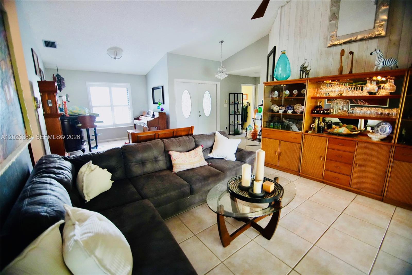 A living room features a dark sectional sofa, a glass coffee table, and a wooden hutch — 150 SW 127th Ave, Plantation FL 33325, PLANTATION, FL