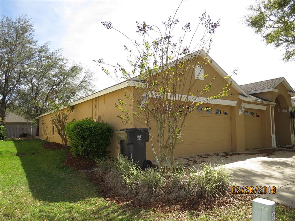 A tan house with a two-car garage and a small tree in the front yard — 9427 HUNTERS POND DRIVE, TAMPA, FL