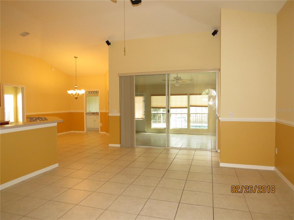 A living area with tile flooring, yellow walls, and sliding glass doors to a patio — 9427 HUNTERS POND DRIVE, TAMPA, FL