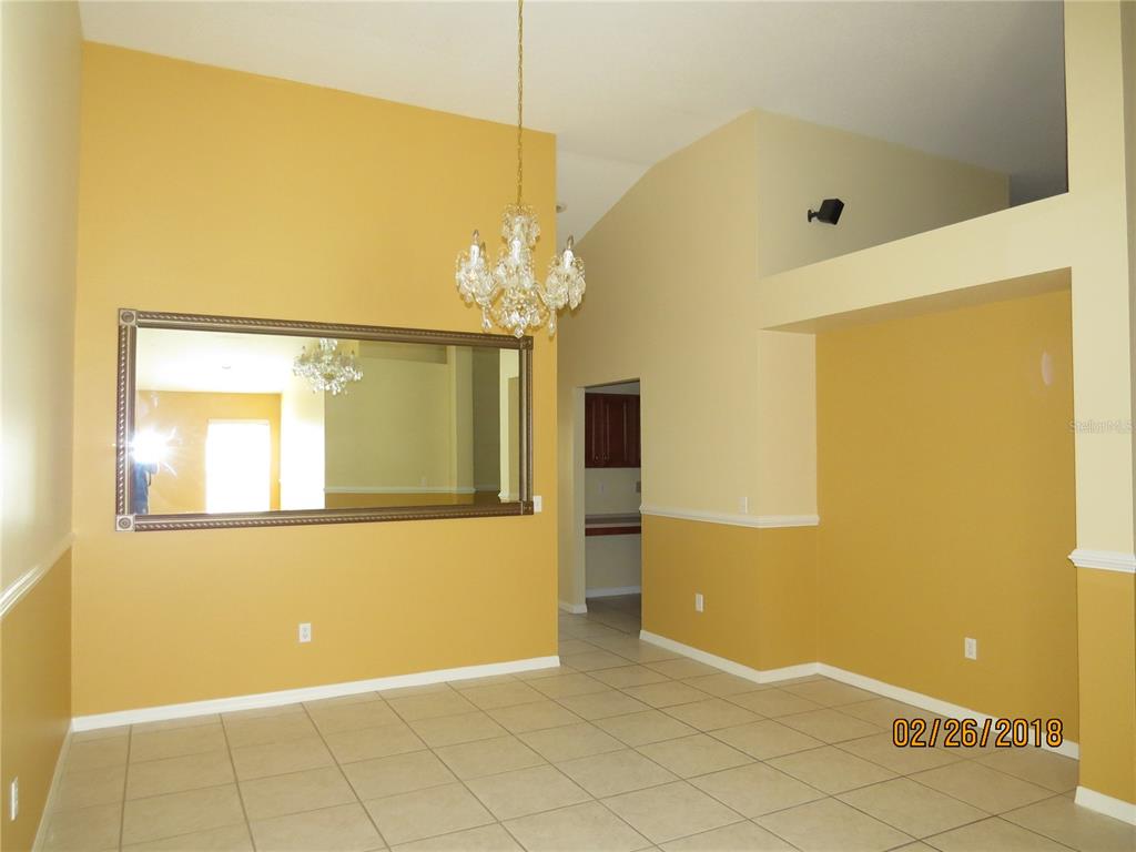 A dining room with a chandelier, a large wall mirror, and yellow two-tone walls — 9427 HUNTERS POND DRIVE, TAMPA, FL