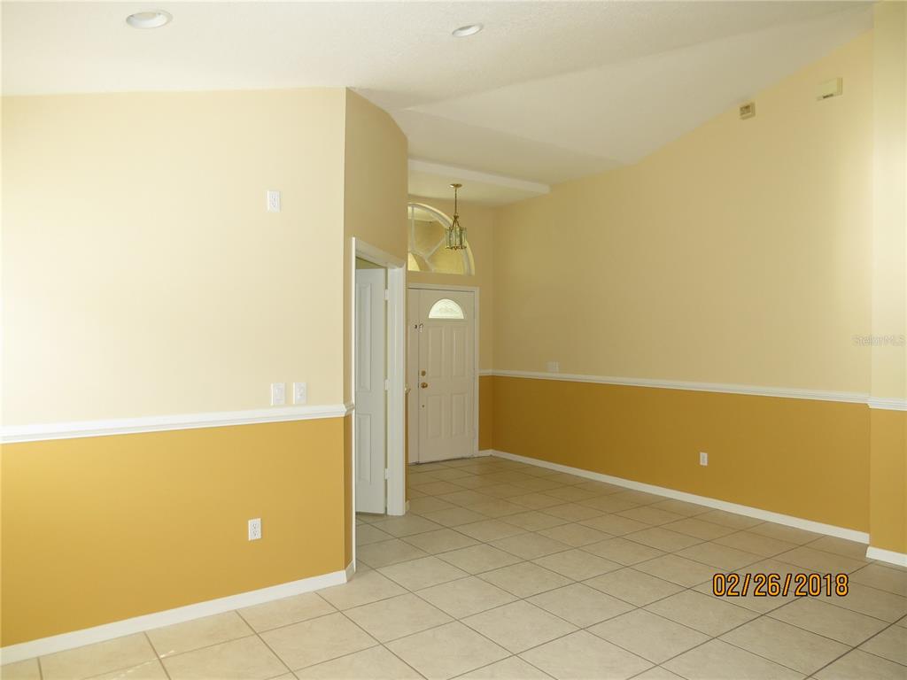 An empty room with tiled floors, two-tone yellow walls, and a white front door — 9427 HUNTERS POND DRIVE, TAMPA, FL