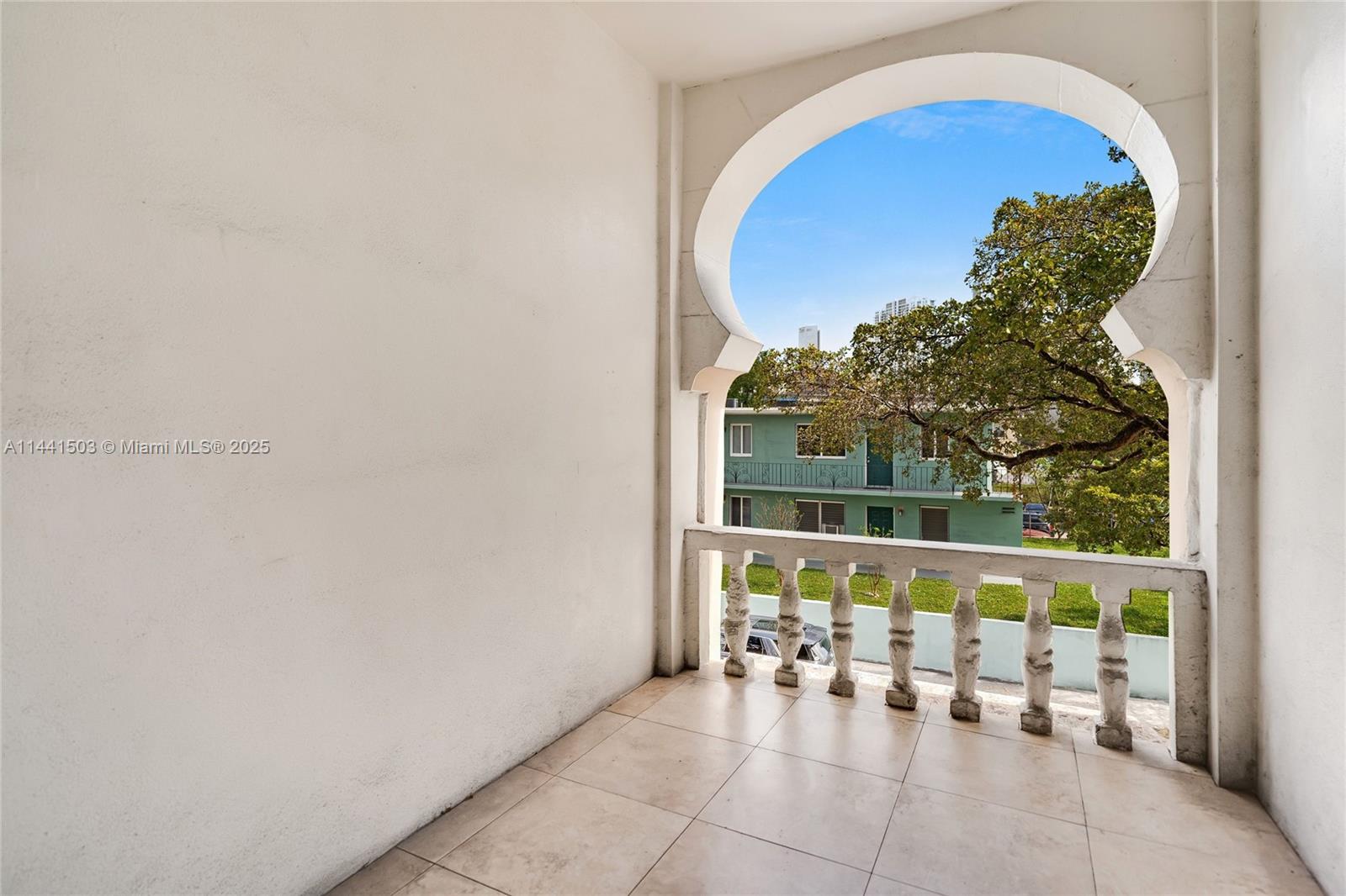 A balcony features tiled flooring, a white balustrade, and a distinctive Moorish-style arched opening — 440 SW 5th Ave, Miami FL 33130, MIAMI, FL