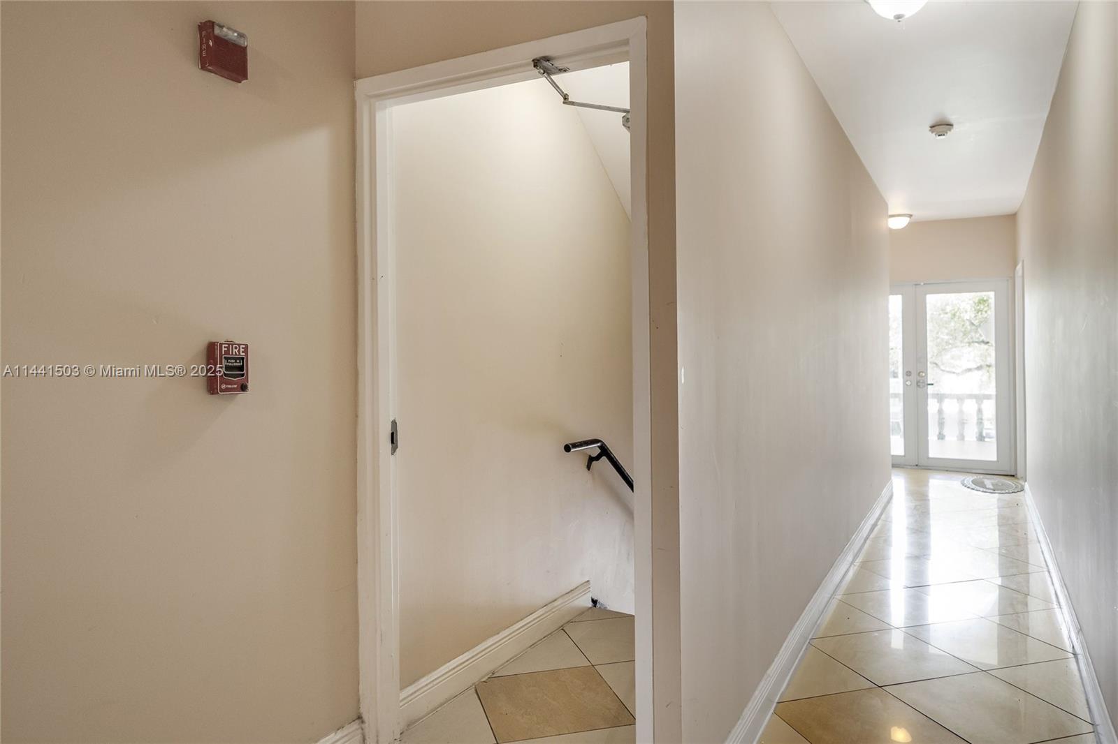 A hallway with tiled floors leads to a glass door, with an adjacent stairwell entrance — 440 SW 5th Ave, Miami FL 33130, MIAMI, FL