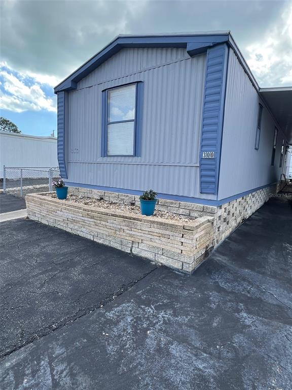 A light blue mobile home features a stone planter box and a paved driveway — 6580 SEMINOLE BOULEVARD UNIT 300, SEMINOLE, FL