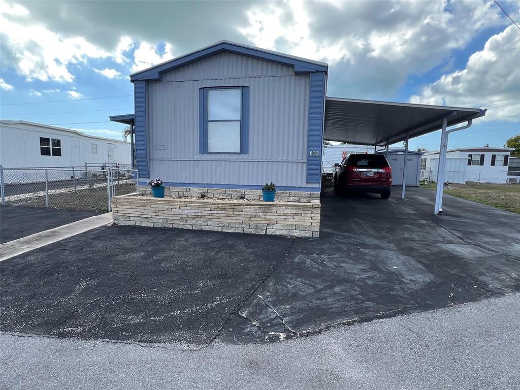 A light blue manufactured home with a stone planter and a covered carport — 6580 SEMINOLE BOULEVARD UNIT 300, SEMINOLE, FL