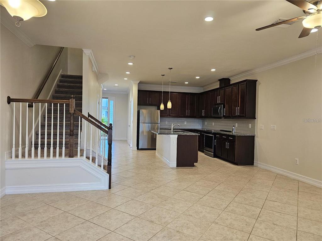 An open-concept kitchen with dark wood cabinets and a staircase with a wooden railing — 3216 PAINTED BLOSSOM COURT, LUTZ, FL