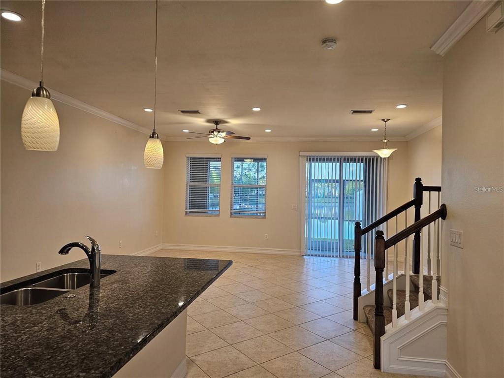 A kitchen island with granite countertops overlooks a living area with tile floors and stairs — 3216 PAINTED BLOSSOM COURT, LUTZ, FL