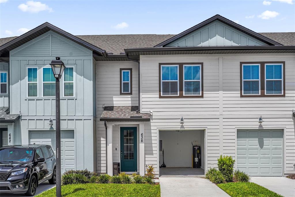 A two-story townhouse exterior features light-colored siding, a front-entry garage, and a teal front door — 638 LONGBOAT DRIVE, DAVENPORT, FL