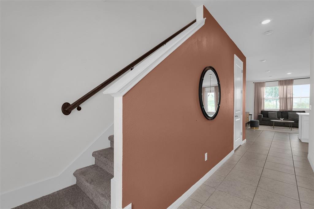A staircase with a dark wood handrail sits beside a terracotta-colored wall with a mirror — 638 LONGBOAT DRIVE, DAVENPORT, FL