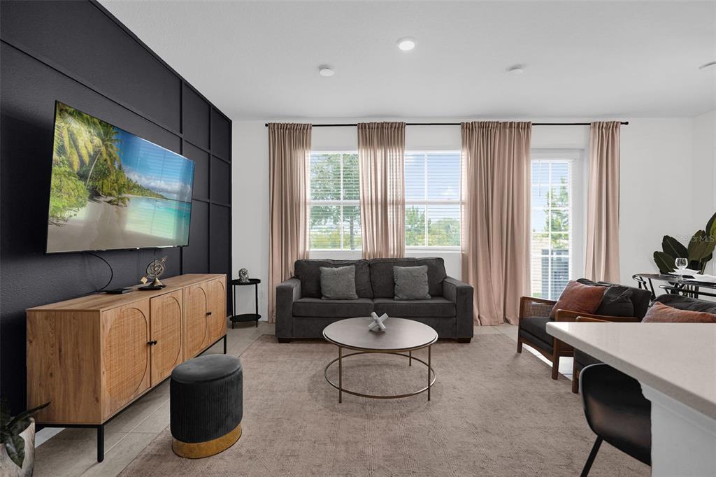 A living room features a dark accent wall with a television, sofa, and light curtains — 638 LONGBOAT DRIVE, DAVENPORT, FL
