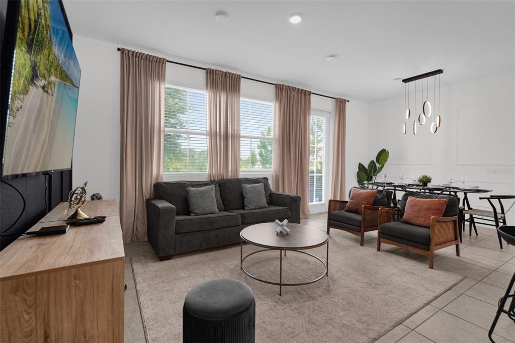 A living room with a grey sofa, two armchairs, a coffee table, and a dining area — 638 LONGBOAT DRIVE, DAVENPORT, FL