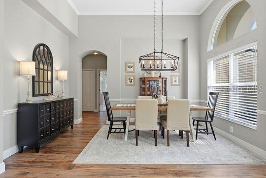 A dining room features a wooden table, upholstered chairs, a chandelier, and a black sideboard — 197 NANDINA TERRACE, WINTER SPRINGS, FL