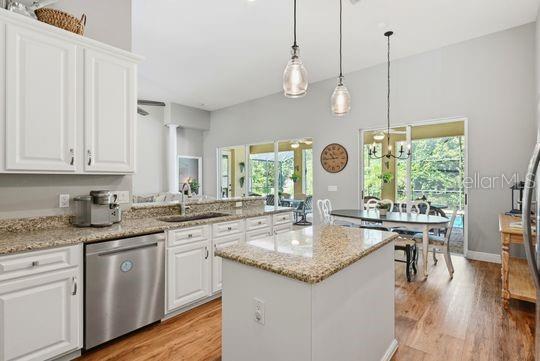 A kitchen with white cabinets, granite countertops, a stainless dishwasher, and an island — 197 NANDINA TERRACE, WINTER SPRINGS, FL