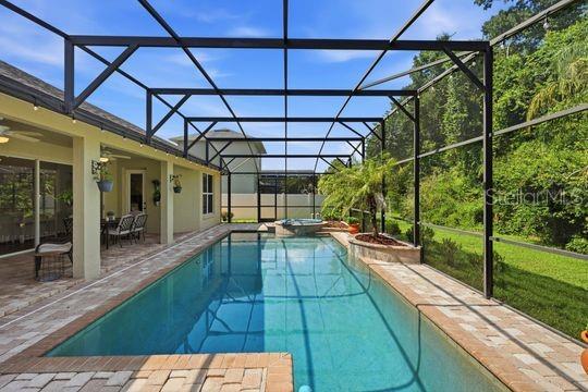A screened-in swimming pool and patio area with brick pavers and a view of trees — 197 NANDINA TERRACE, WINTER SPRINGS, FL