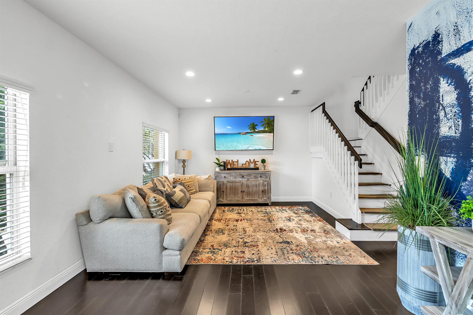 A living room features a grey sofa, a patterned rug, a television, and a staircase — 364 Lake Monterey Circle, Boynton Beach FL 33426, BOYNTON BEACH, FL