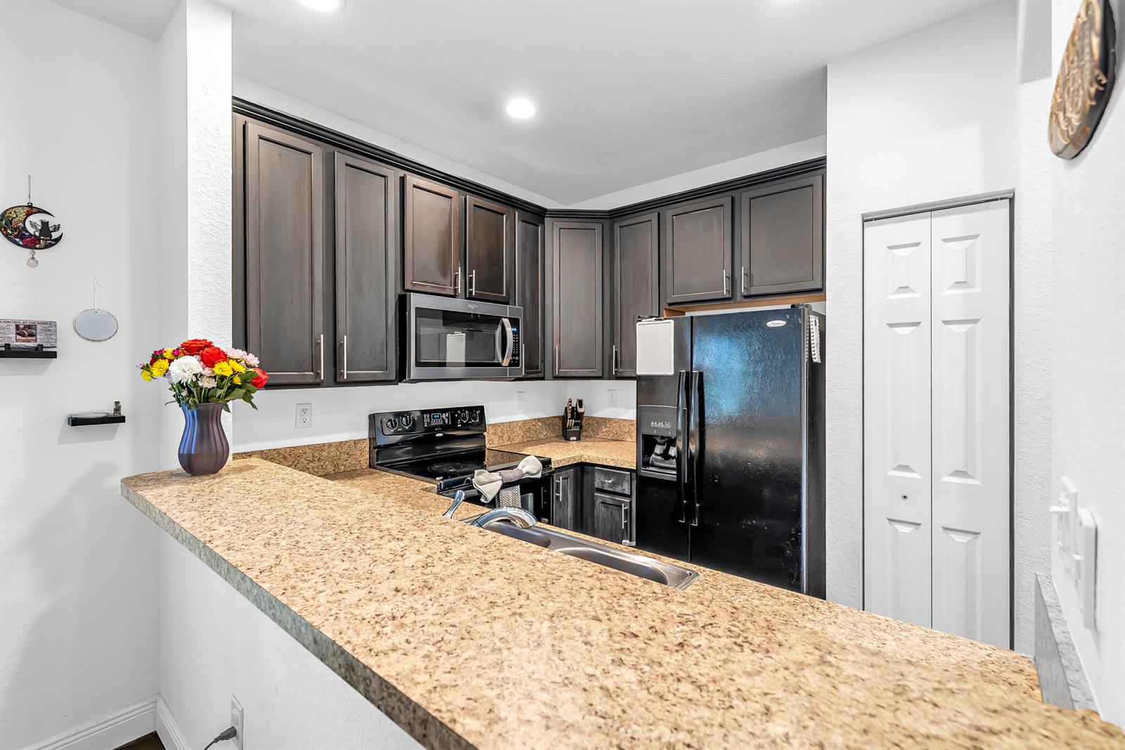 A kitchen features dark wood cabinets, granite countertops, a black refrigerator, and a breakfast bar — 364 Lake Monterey Circle, Boynton Beach FL 33426, BOYNTON BEACH, FL