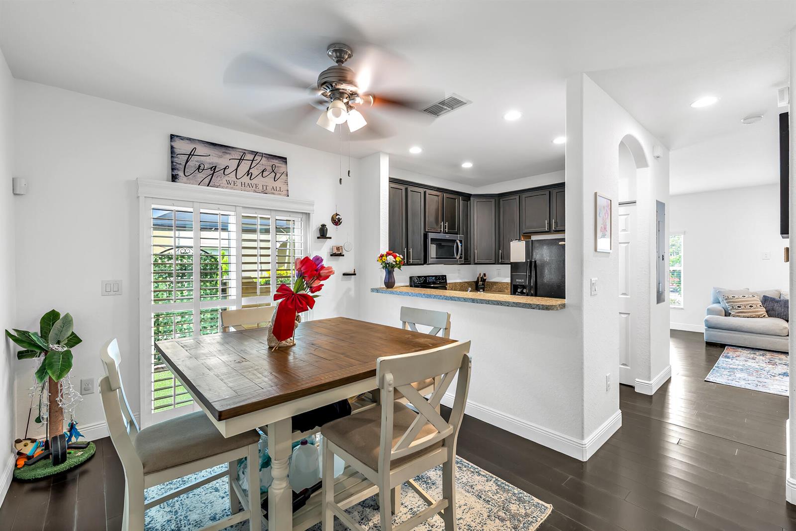 A dining area with a wooden table and chairs sits adjacent to a kitchen with dark cabinets — 364 Lake Monterey Circle, Boynton Beach FL 33426, BOYNTON BEACH, FL