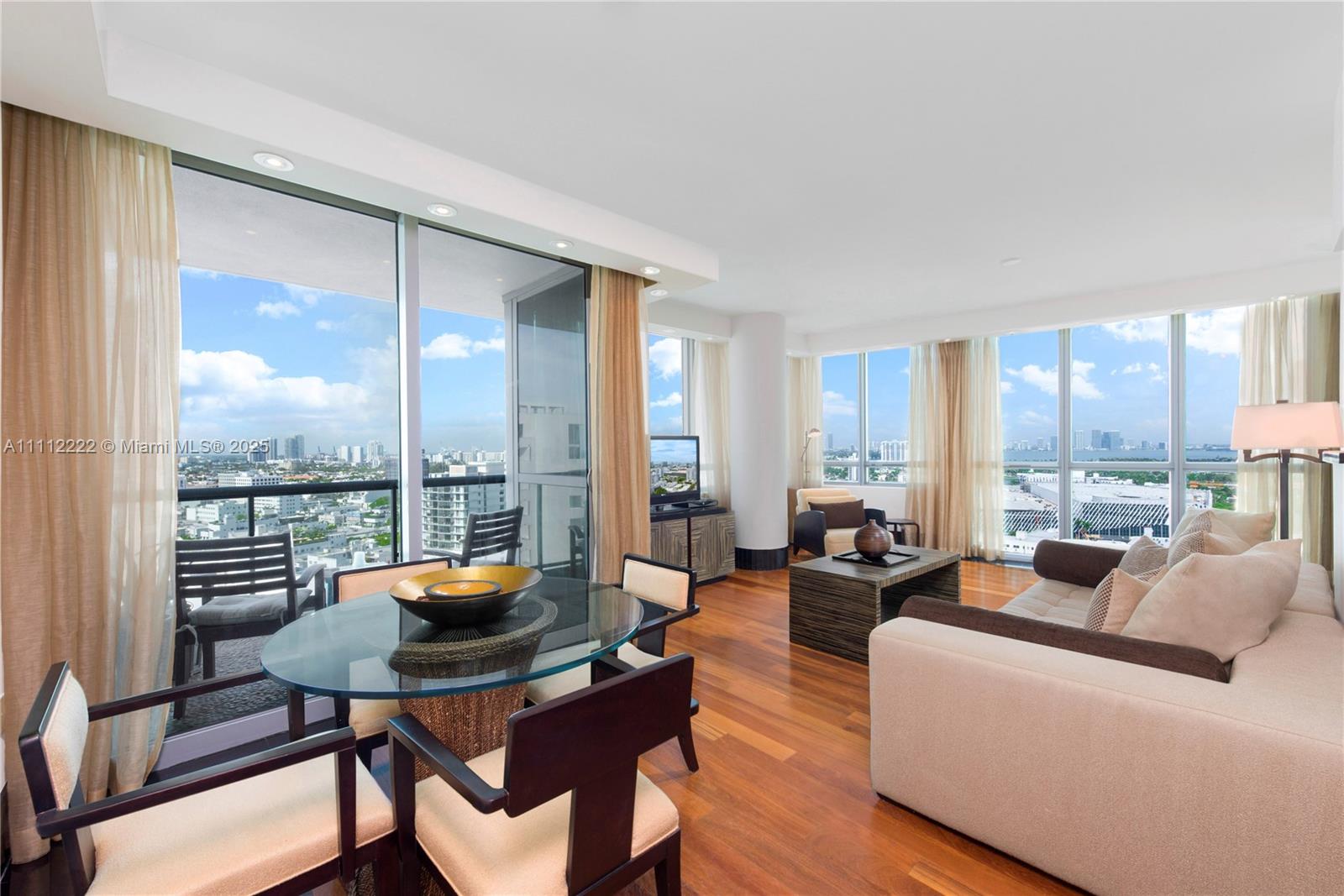 A living and dining area features floor-to-ceiling windows, hardwood floors, and a city view — 101 20th St # 2402, Miami Beach FL 33139, MIAMI BEACH, FL