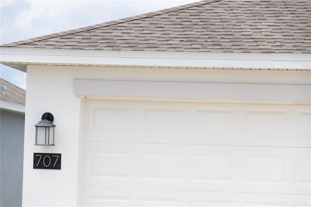 A white garage door with a house number plaque and a wall-mounted light fixture — 707 STAFFORA STREET, HAINES CITY, FL
