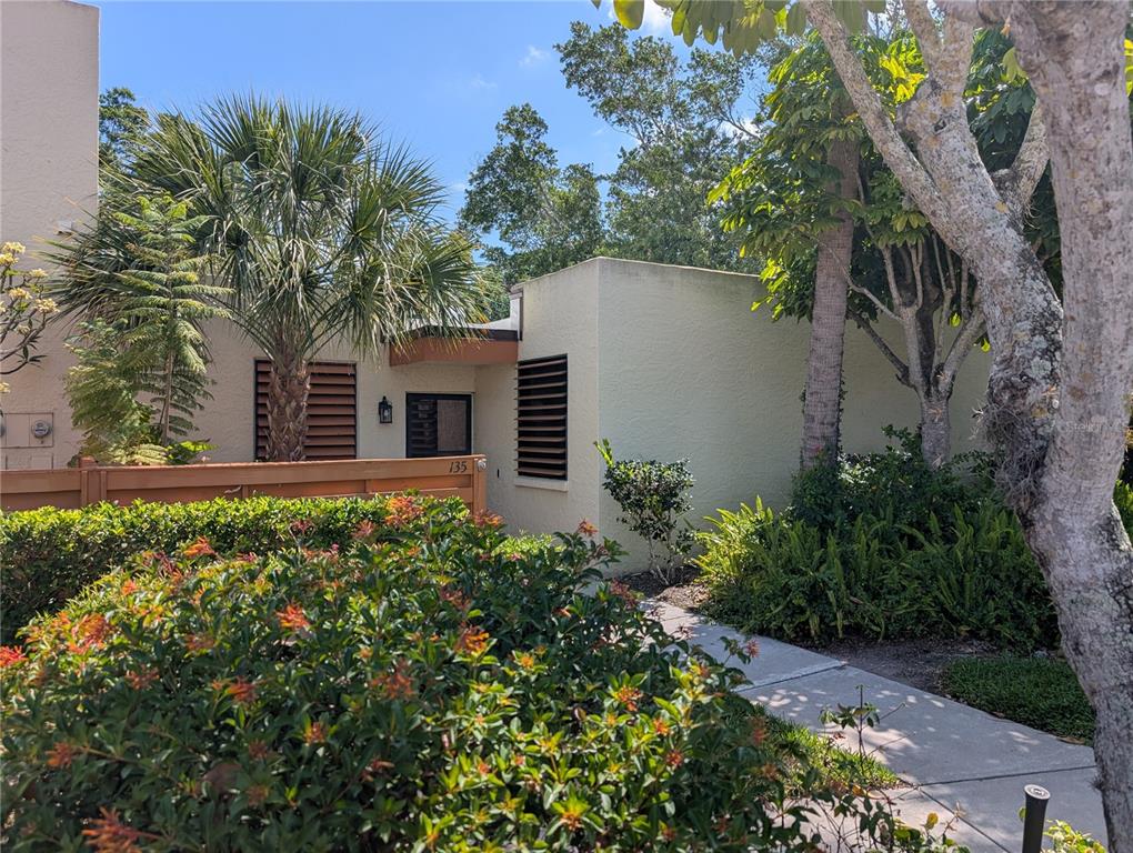 A low-slung, light-colored stucco building features dark louvered shutters and a palm tree out front — 135 WILD PALM DRIVE, BRADENTON, FL
