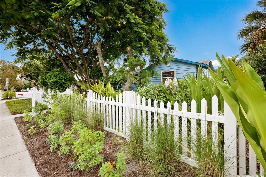 A white picket fence borders a garden in front of a blue house — 2070 HYDE PARK STREET, SARASOTA, FL