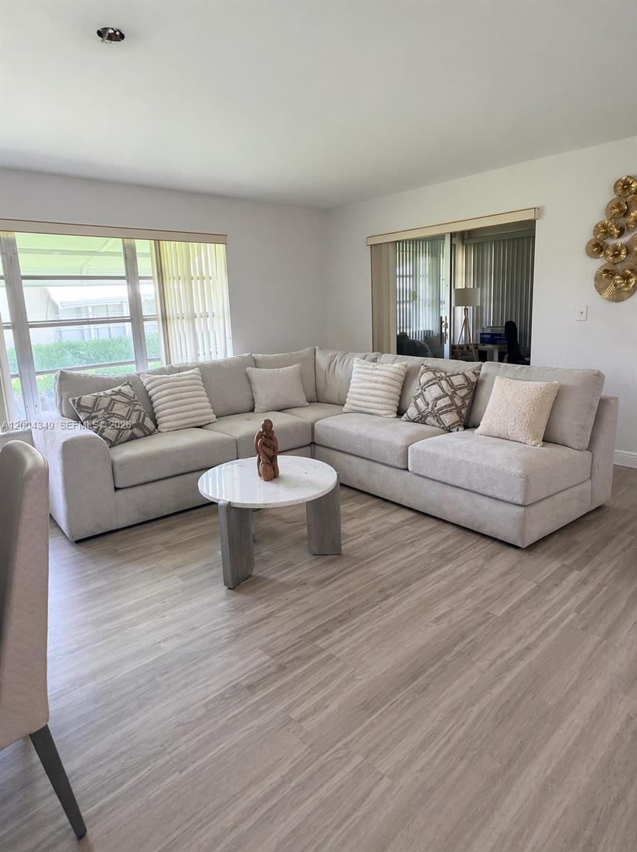A living room features a large sectional sofa, a round marble coffee table, and light-colored flooring — 200 High Point Ct E # D, Delray Beach FL 33445, DELRAY BEACH, FL