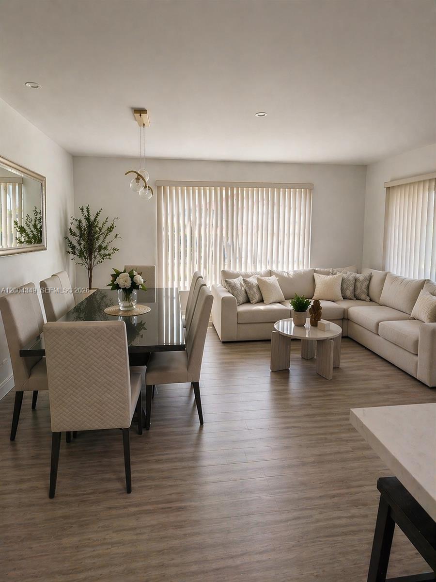 A dining area and living room feature light wood flooring, neutral furniture, and vertical blinds — 200 High Point Ct E # D, Delray Beach FL 33445, DELRAY BEACH, FL