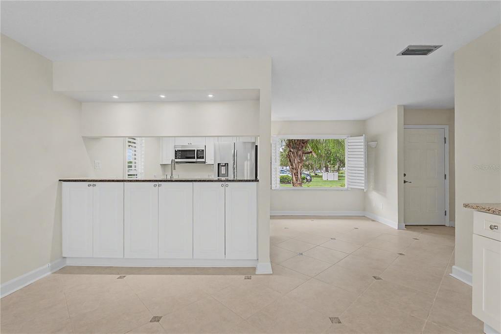 A kitchen with white cabinets and a breakfast bar opens into a dining area — 11364 W BAYSHORE DRIVE, CRYSTAL RIVER, FL