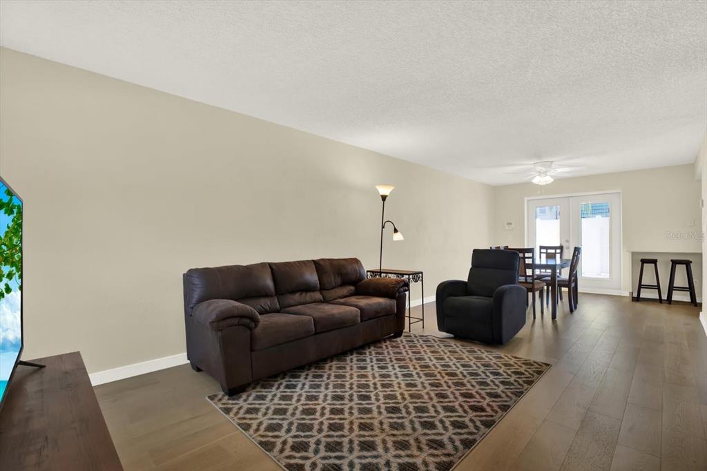 A living room features a brown sofa, a recliner, and a dining area with wood floors — 1799 N HIGHLAND AVENUE UNIT 53, CLEARWATER, FL