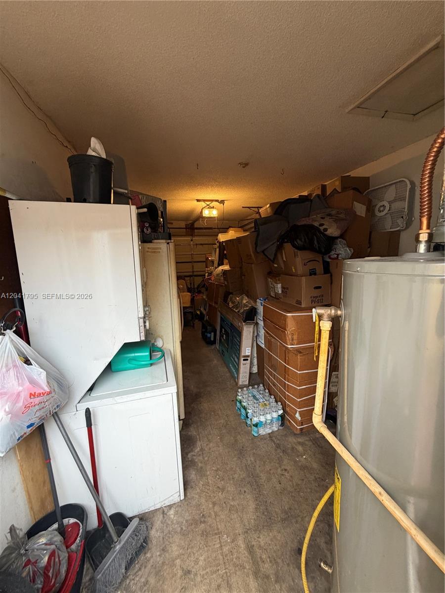 A cluttered garage contains a water heater, a washer and dryer, and stacked cardboard boxes — 11511 SW 83rd Ter, Miami FL 33173, MIAMI, FL