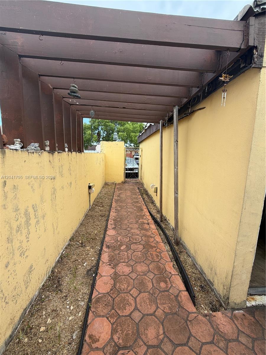 A narrow outdoor walkway features a paved path covered by a wooden pergola structure — 11511 SW 83rd Ter, Miami FL 33173, MIAMI, FL