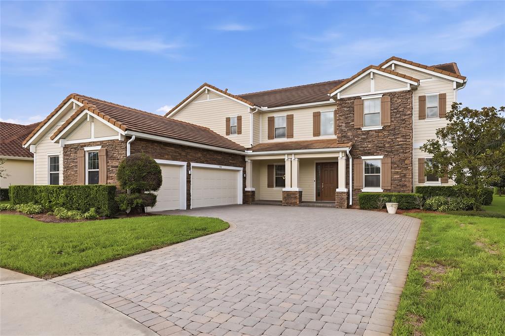 A two-story house with a stone and beige siding facade, tile roof, and paved driveway — 504 CINDER POINT, SANFORD, FL