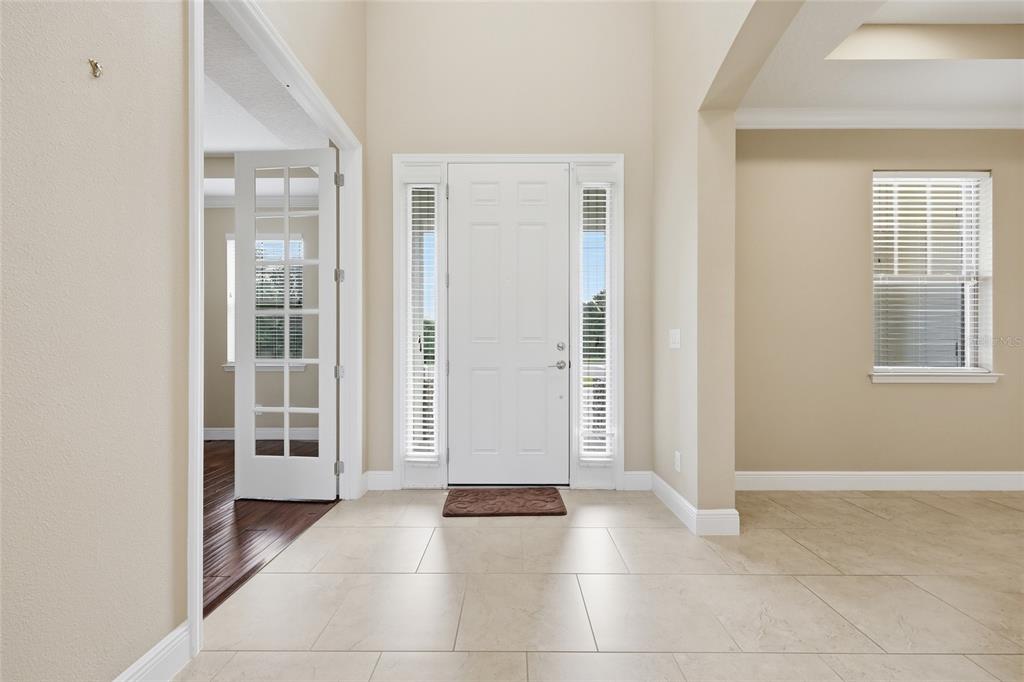 A bright entryway features light-colored tile flooring, a white front door, and French doors — 504 CINDER POINT, SANFORD, FL