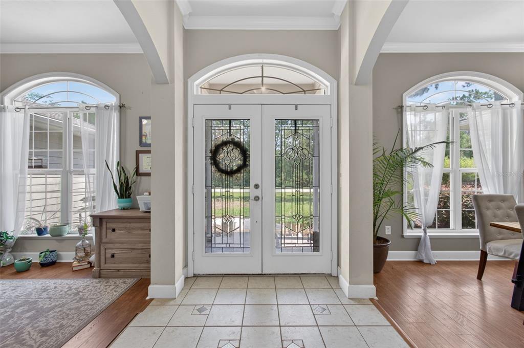 An entryway features a tiled floor, double glass-paneled doors, and large windows with white curtains — 24865 NW 155TH AVENUE, HIGH SPRINGS, FL