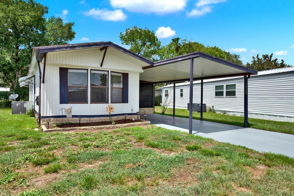 A white manufactured home with a carport and a small front garden area — 34421 COUNTRYSIDE DRIVE, WESLEY CHAPEL, FL