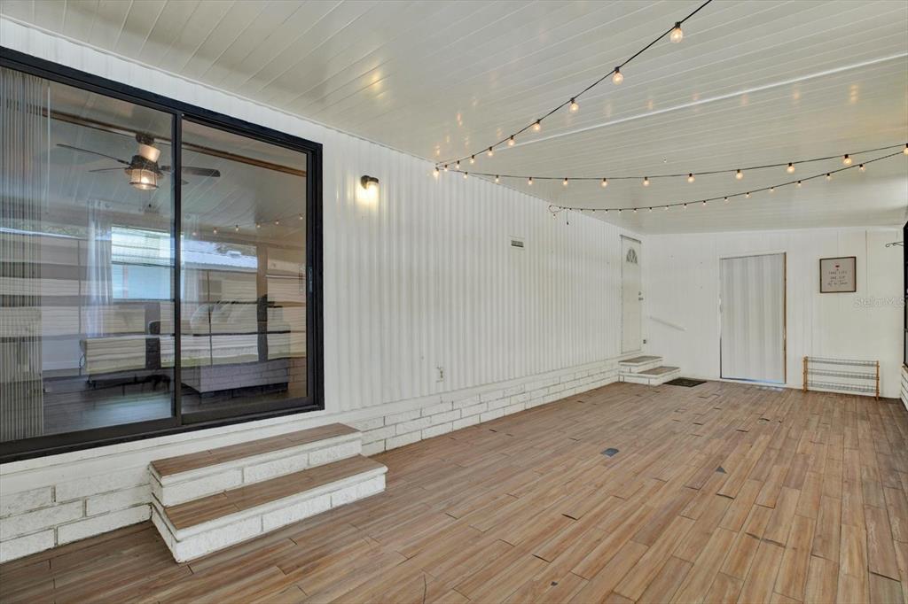A covered patio with wood-look tile flooring, white corrugated walls, and string lights — 34421 COUNTRYSIDE DRIVE, WESLEY CHAPEL, FL
