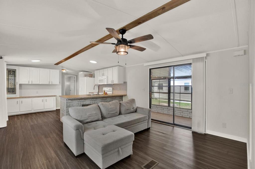 A living room with a gray sectional sofa, wood-look flooring, and an open kitchen — 34421 COUNTRYSIDE DRIVE, WESLEY CHAPEL, FL