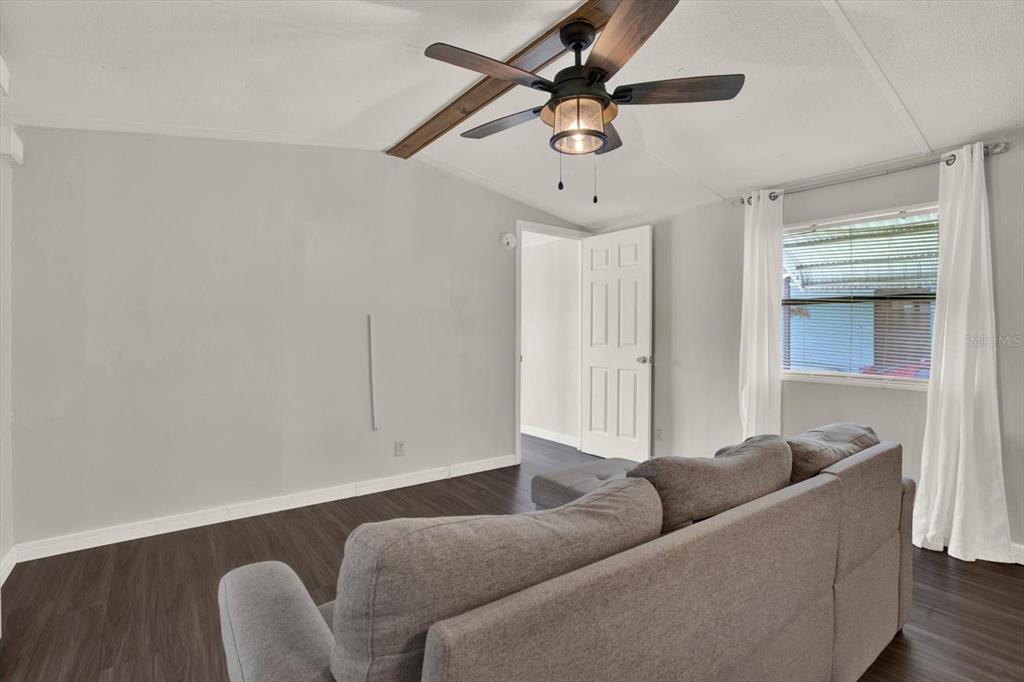 A living room features gray walls, dark wood-look flooring, a ceiling fan, and a sofa — 34421 COUNTRYSIDE DRIVE, WESLEY CHAPEL, FL